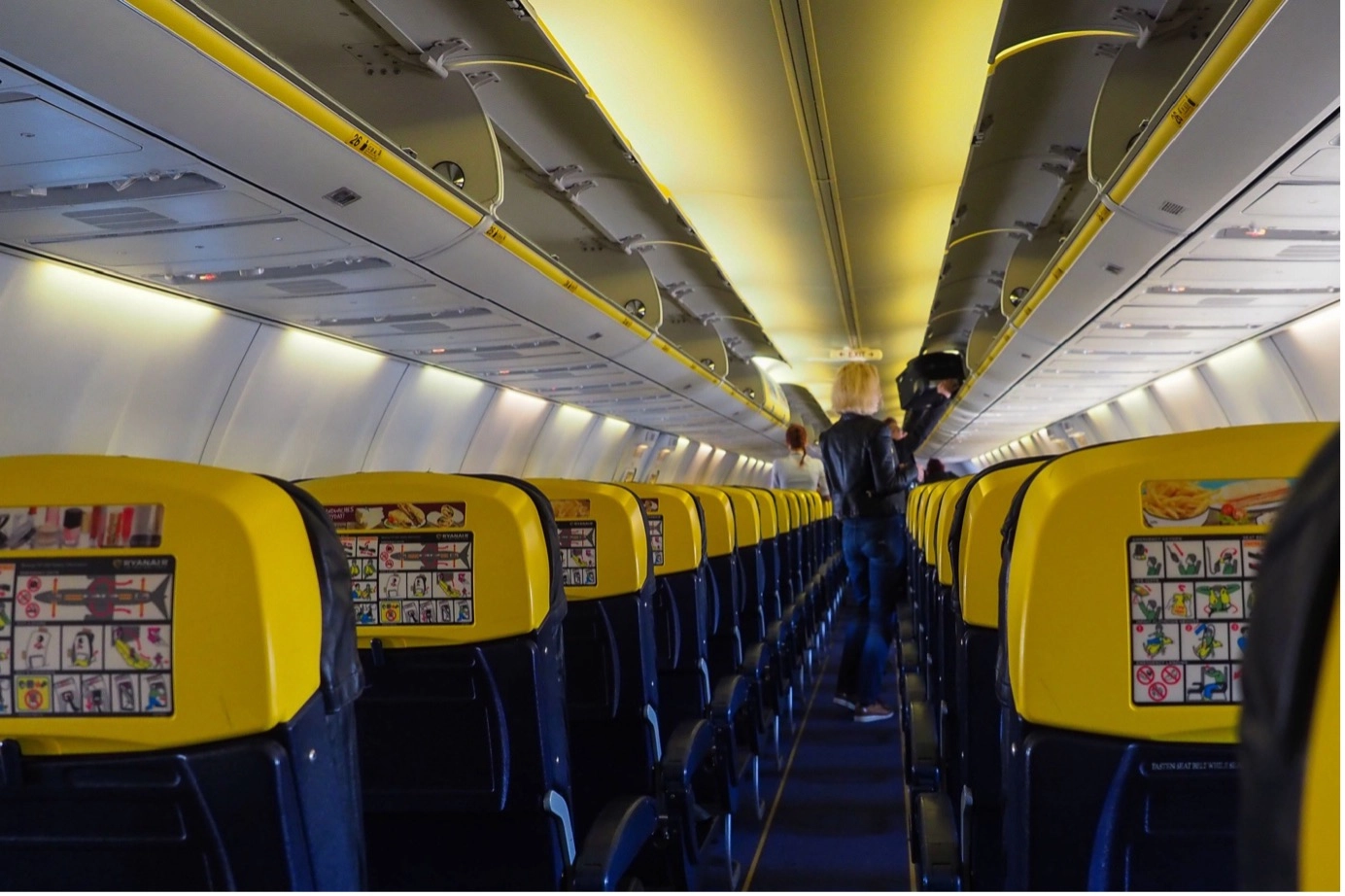 Passengers boarding inside the airplane. Yellow blue airplane chairs.