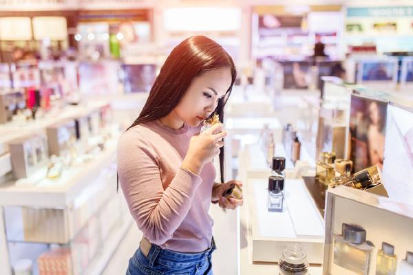 Woman testing and choosing to buy perfume in duty-free store